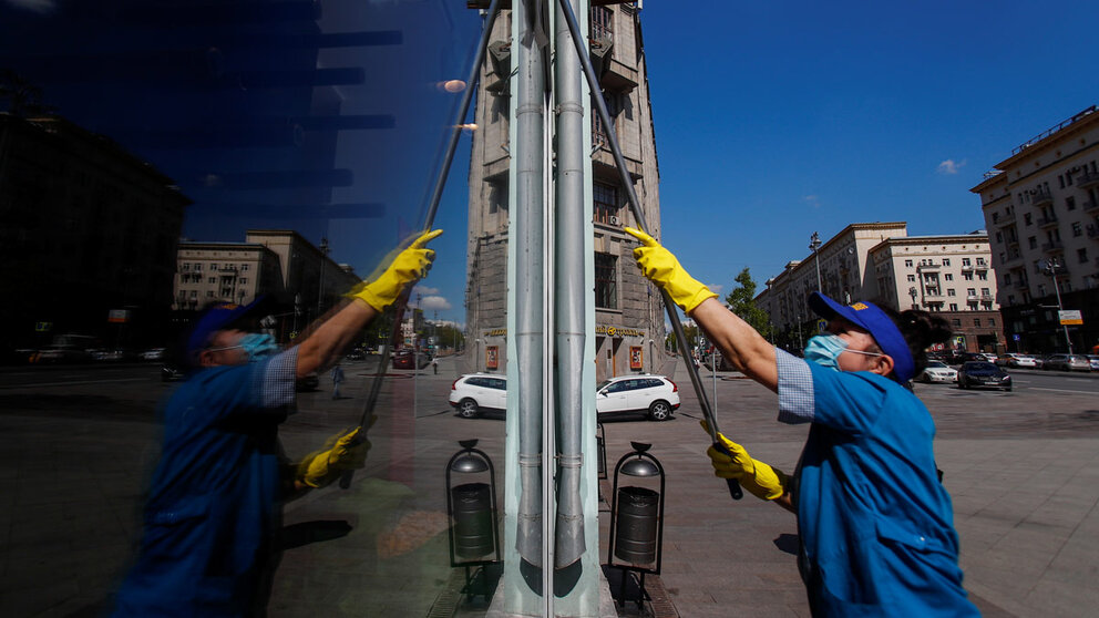 A woman wearing a protective face mask washes the window of a store amid the outbreak of the coronavirus disease (COVID-19) in Moscow, Russia May 28, 2020. REUTERS/Maxim Shemetov